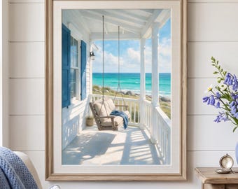 May include: A framed wall art print depicting a coastal porch with a hanging swing, blue shutters, and an ocean view. Beside it, a light blue ceramic pitcher holds a bouquet of bluebells and white daisies on a wooden console table.