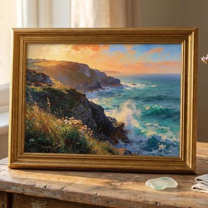 Può includere: Un dipinto paesaggistico incorniciato di una scena costiera con un tramonto dorato. L'opera d'arte mostra una scogliera rocciosa, onde che si infrangono e un cielo vibrante. La cornice è dorata e il dipinto è esposto su un tavolo di legno.