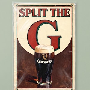 May include: A framed Guinness advertisement with the text "SPLIT THE G" in red letters. A pint of Guinness stout with a creamy head is in the center. The background is a dark brown color.