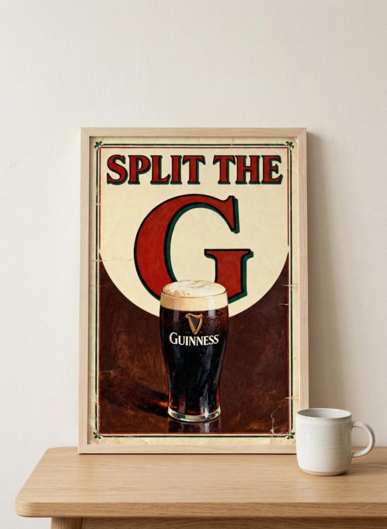 May include: Vintage-style framed print featuring a pint of Guinness stout. The artwork includes the text "SPLIT THE G" in red and green, with a creamy white head on the dark beer. A white mug sits on a wooden surface.