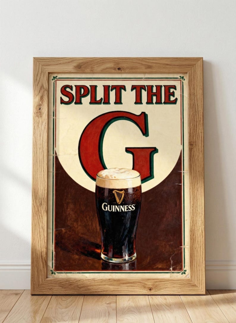 May include: Framed vintage-style Guinness beer advertisement. The poster features a pint of dark stout with a creamy head, set against a brown and cream background. The text "SPLIT THE G" is prominently displayed in red.