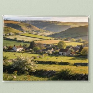 May include: A scenic landscape photograph of a rural village nestled in a valley. The image features rolling green hills, fields, and houses with stone walls. The photograph is encased in a clear plastic sleeve.