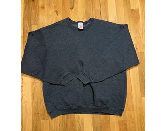 May include: A dark gray Wilson brand sweatshirt with a crew neck and long sleeves. The sweatshirt has a tag on the collar and is made of a soft, comfortable material. The cuffs and hem are ribbed.