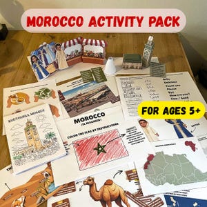 May include: A collection of educational materials labeled "MOROCCO ACTIVITY PACK" for ages 5+. Includes illustrated pages with the Koutoubia Mosque, a map, and instructions to color the Moroccan flag. Also features paper cutouts of figures and market stalls.