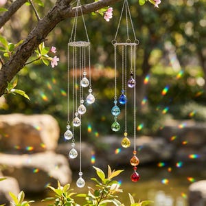 May include: Two hanging crystal suncatchers suspended from silver-toned chains. One features clear, faceted spherical crystals, while the other displays a vertical arrangement of teardrop-shaped crystals in a spectrum of rainbow colours.