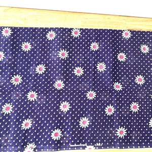 Peut inclure: Un tissu bleu marine avec un motif de pois blancs et des marguerites blanches &agrave; c&oelig;ur rose. Le tissu rectangulaire pourrait &ecirc;tre un chemin de table ou un tissu d&eacute;coratif.