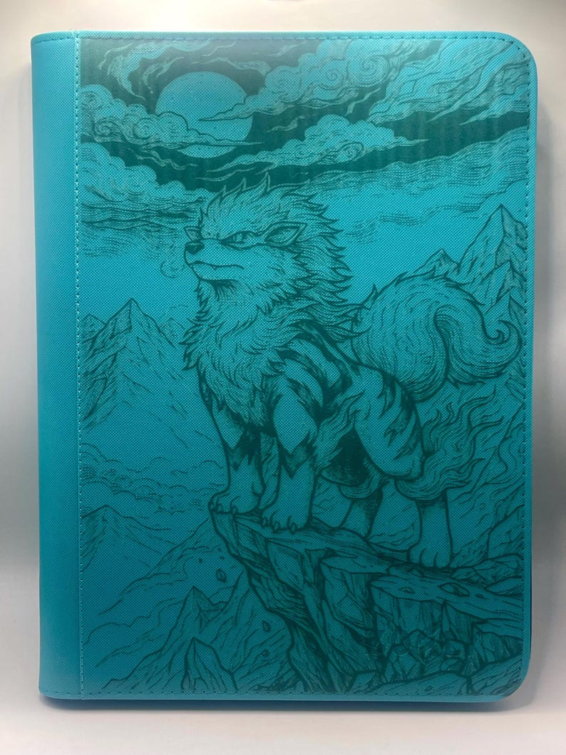 May include: Teal card binder featuring a detailed illustration of a wolf-like creature on a cliff, with mountains and a moon in the background. The design is in a darker teal, creating a textured, artistic look. The spine is a solid teal.