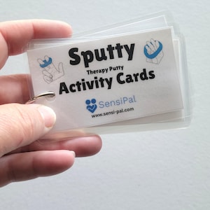 May include: A set of "Sputty Therapy Putty Activity Cards" held by a hand. The cards are white with black text and blue graphics. The SensiPal logo and website address are also visible.
