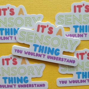 May include: Four white stickers with colorful text that reads "It's a sensory thing you wouldn't understand". The stickers are on a yellow background.