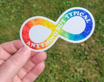 May include: A sticker in the shape of an infinity symbol with a watercolor rainbow gradient. The sticker has the words "ANYTHING BUT TYPICAL" in white text, promoting neurodiversity awareness.