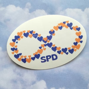 May include: An oval sticker featuring an infinity symbol made of blue and orange hearts. The word "SPD" is printed in blue at the bottom. The sticker is on a light blue background.