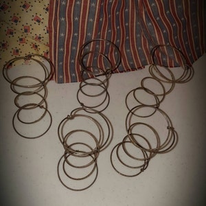 May include: Three sets of metal rings, possibly for a craft project, are arranged in the foreground. The background features patriotic fabric with American flags and red, white, and blue stripes and stars.