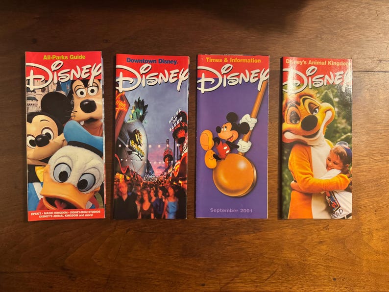 K&ouml;nnte beinhalten: Vier Disney-Parkf&uuml;hrer. Die Cover zeigen Micky Maus, Goofy, Donald Duck und Szenen aus den Parks. Ein F&uuml;hrer ist lila mit Micky Maus und dem Text "September 2001."