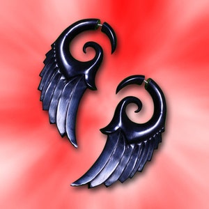 K&ouml;nnte beinhalten: Ein Paar schwarze Holz-Ohrenstrecker mit Fl&uuml;gel- und Spiraldesign.