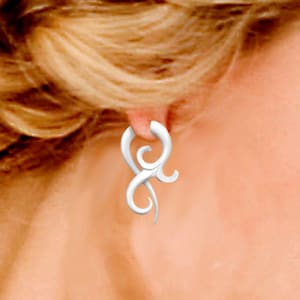 May include: A white metal earring with a unique, intricate design. The earring is shaped like a stylized swirl or flame.