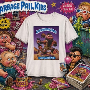 May include: White t-shirt featuring a graphic from the Garbage Pail Kids series. The shirt's design includes the text "GARBAGE PAIL KIDS" and "BRUTAL BRAD". The background features other Garbage Pail Kids characters and text.