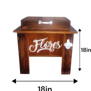 May include: A wooden cooler with a dark stain, featuring the word "Flores" in white script. The cooler has a lid and a bottle opener. It measures 18 inches in height and 18 inches in width.