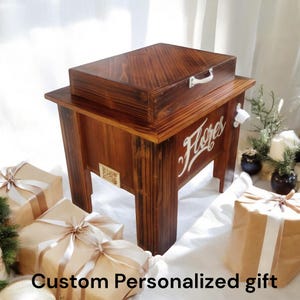 May include: A wooden cooler with a dark stain, featuring a hinged lid and a bottle opener. The word "Flores" is painted in white script on the front. The text "Custom Personalized gift" is at the bottom.