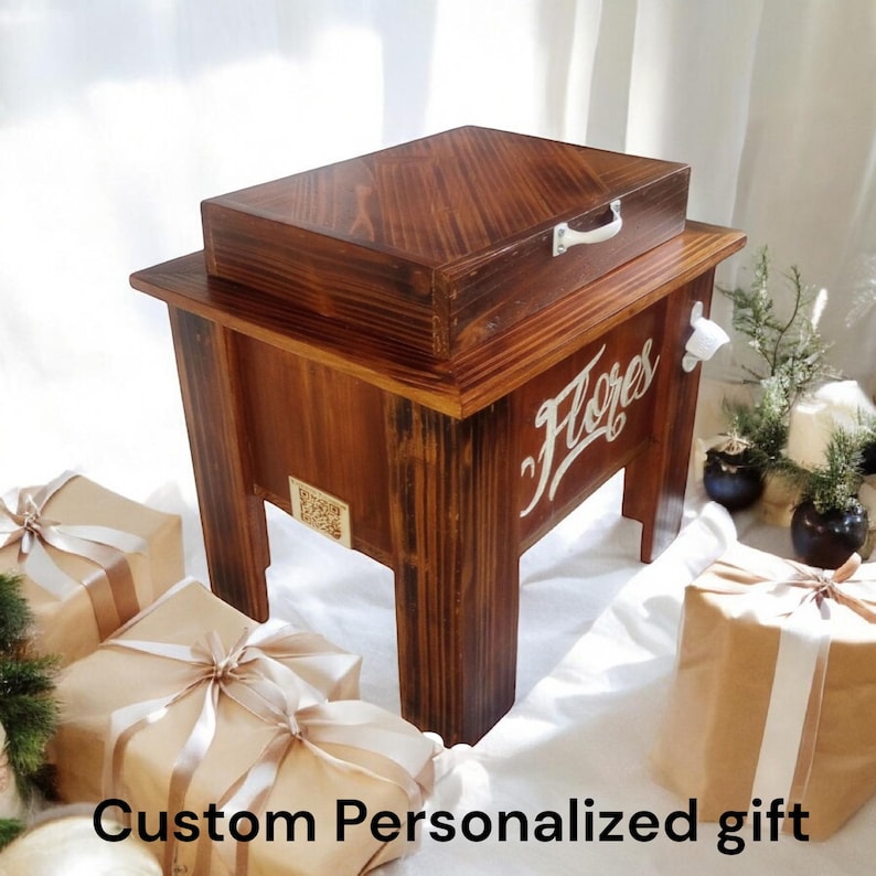 May include: A wooden cooler with a dark stain, featuring a hinged lid and a bottle opener. The word "Flores" is painted in white script on the front. The text "Custom Personalized gift" is at the bottom.