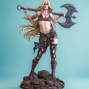May include: A detailed figurine of a warrior woman with long blonde hair, holding a large battle axe. She wears a dark brown leather bikini top, skirt, and boots, with decorative markings on her arms and face. The figure stands on a rocky base.
