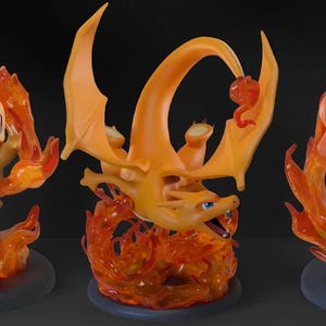 May include: Three orange and yellow creature figurines displayed on circular bases. The left figure is small with a flame ring, the center figure is winged and flying above flames, and the right figure stands on a rocky base with fire effects.