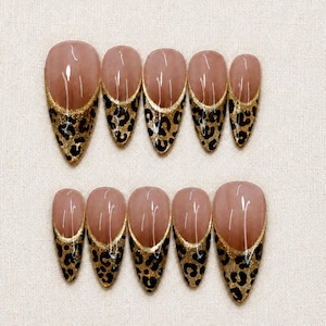 Puede incluir: Un juego de diez uñas postizas en forma de almendra con una base de color nude. Cada uña tiene un diseño de punta francesa con un fondo de purpurina dorada y un estampado de leopardo negro. Las uñas tienen un acabado brillante y están en dos filas.