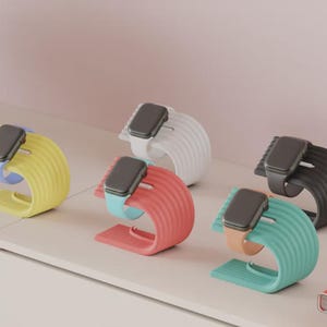 May include: A collection of colorful watch stands in yellow, white, red, black, and teal. Each stand holds a smartwatch with a matching or complementary band. The stands have a curved, ribbed design.