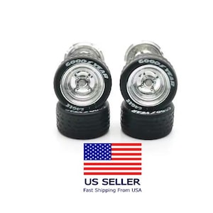 May include: Four miniature car wheels with black tires and silver rims. The tires have the Goodyear and Eagle brand names in white lettering. The wheels are stacked in pairs on a white background.