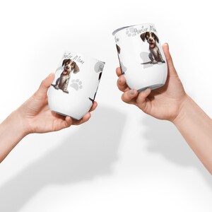 Könnte beinhalten: Zwei weiße Edelstahl-Weintumbler mit einer Cartoon-Illustration eines Deutsch Kurzhaar Hundes. Die Tumbler tragen den Text "Pointer Mom" und ein Pfotenabdruck-Design.