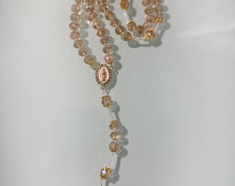 Handmade rosary featuring champagne-gold faceted beads, gold-tone accents, a Blessed Virgin Mary center medal, and an ornate gold crucifix
