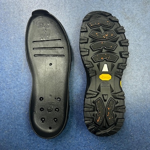May include: Black shoe insoles and a black shoe sole with a textured tread pattern. The insole has the text "S1374" and other markings. The sole has the "Vibram" logo and orange accents.