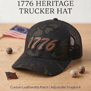 May include: A black camouflage trucker hat featuring a brown leatherette patch with the text 1776. The hat includes an adjustable snapback closure and mesh back panels. Text on the image reads: COMMEMORATE THE USA 250th ANNIVERSARY 1776 HERITAGE TRUCKER HAT Custom Leatherette Patch | Adjustable Snapback.