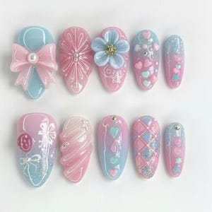 Peut inclure: Dix faux ongles aux couleurs pastel rose et bleu. Les ongles sont orn&eacute;s de n&oelig;uds, de fleurs, de c&oelig;urs et de paillettes. Certains ongles pr&eacute;sentent des &eacute;l&eacute;ments en 3D, tandis que d'autres arborent des motifs peints d&eacute;taill&eacute;s, pour un effet fantaisiste.