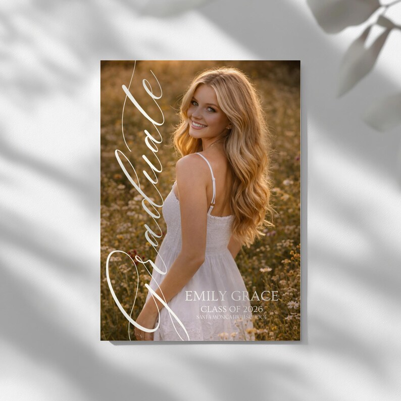 Peut inclure: Annonce de remise de dipl&ocirc;me avec une femme souriante en robe blanche dans un champ de fleurs. Le mot "Graduate" est &eacute;crit en script. L'annonce comprend le nom "Emily Grace" et "Class of 2026".