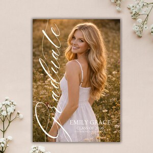 Peut inclure: Annonce de remise de dipl&ocirc;me avec une jeune femme blonde souriante en robe blanche, dans un champ de fleurs sauvages. Le mot "Graduate" est &eacute;crit en script &eacute;l&eacute;gant. L'annonce comprend le nom "Emily Grace" et "Classe de 2026, Santa Monica High School."