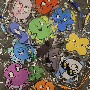 Puede incluir: Una colección de llaveros acrílicos coloridos con personajes de números de dibujos animados. Cada llavero presenta un diseño de número diferente, con varios colores como azul, verde, amarillo y morado. Tienen cordones trenzados adjuntos.