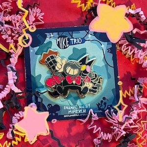 Puede incluir: Pin esmaltado con un diseño de trío de dibujos animados y el texto "Mike Trio". El pin tiene un fondo azul con un borde negro y está rodeado de papel rojo, amarillo y rosa. Diseñado por Mipexch.