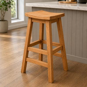 Puede incluir: Un taburete de bar de madera de color marrón claro con un asiento curvado en forma de silla de montar y cuatro patas rectas conectadas por barras de soporte horizontales en los cuatro lados. El taburete tiene un acabado de veta de madera natural.