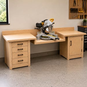 May include: A light-colored wooden workbench featuring a recessed center section holding a yellow and black miter saw. The left side has four stacked drawers with black handles, while the right side features a single cabinet door with a black handle.