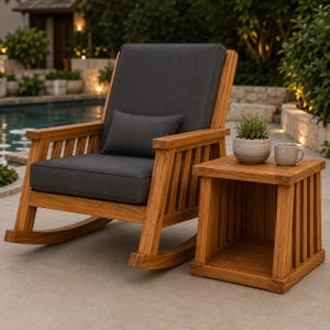May include: A wooden rocking chair with dark grey cushions and a matching lumbar pillow, positioned next to a square wooden side table. The side table holds a small potted green plant and a light grey ceramic mug on its flat top surface.