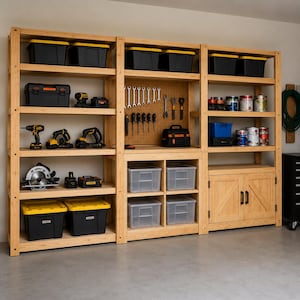May include: A large light-colored wooden shelving unit with three vertical sections. The unit features open shelves holding black and yellow storage bins, power tools, and paint cans. A central pegboard displays various hand tools, and a lower cabinet.