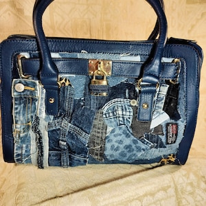 以下が含まれることがあります： デニムとレオパード柄の生地で作られたパッチワークデザインのネイビーブルーのハンドバッグ。バッグは長方形で、ゴールドカラーのロックと2つのネイビーブルーのハンドルが付いています。バッグの側面にはデニムポケットが付いています。