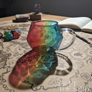 Peut inclure: Une tasse en verre multicolore en forme de dé à vingt faces, avec des chiffres visibles sur ses facettes. La tasse projette une ombre arc-en-ciel sur une surface en forme de carte. D'autres dés et un carnet sont également visibles.