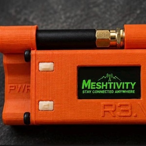 May include: A bright orange rectangular electronic device with a black antenna, two white buttons, and a screen displaying the green text MESHTIVITY STAY CONNECTED ANYWHERE. The casing features embossed labels PWR and R3.V on the front surface.
