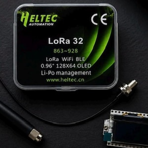 May include: A Heltec Automation LoRa 32 development board with a 0.96 inch OLED display, a black antenna, and a clear plastic storage case. The case label reads LoRa 32, 863-928, LoRa WiFi BLE, 0.96 inch 128X64 OLED, Li-Po management, and www.heltec.cn.