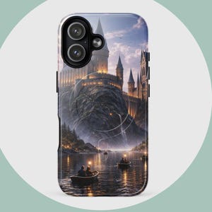 May include: A phone case featuring a detailed illustration of a castle on a mountain overlooking a lake with small boats. The castle is lit up with lights, and the sky is a mix of blue and orange.