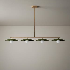 May include: A modern, linear chandelier with four lights. The fixture features a brass finish and olive green shades. Each shade has a white, spherical light bulb. The design is minimalist and suitable for a dining room or kitchen.