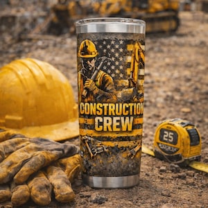 Może przedstawiać: Kubek ze stali nierdzewnej o tematyce budowlanej. Projekt przedstawia robotnika budowlanego, amerykańską flagę oraz słowa "CONSTRUCTION CREW" w kolorze żółtym i czarnym. Widoczny jest również żółty kask, rękawice robocze i miarka.
