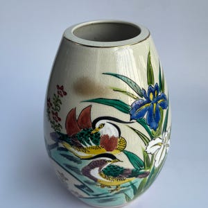 Può includere: Un vaso in ceramica color crema con finitura a smalto crettato, caratterizzato da una scena dipinta a mano di due colorate anatre mandarine che nuotano tra canne verdi, fiori di iris blu e bianchi e un bordo rifinito in oro.
