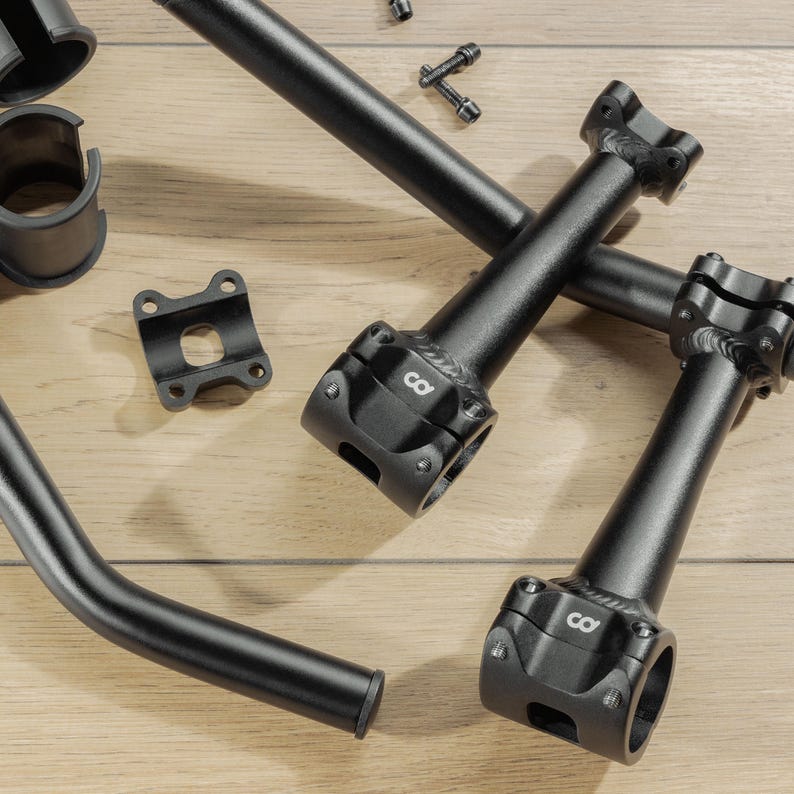 Puede incluir: Un surtido de componentes negros de bicicleta, incluyendo manillares, potencias y herrajes, se disponen sobre una superficie de madera clara. Las potencias presentan un dise&ntilde;o distintivo con el n&uacute;mero "8". Los componentes parecen nuevos y sin usar.